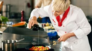 A female chef putting olive oil on a salad, uncovering the rich flavors of your city's diverse culinary scene.